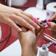 From above of crop unrecognizable manicurist doing nail art for female client in beauty salon